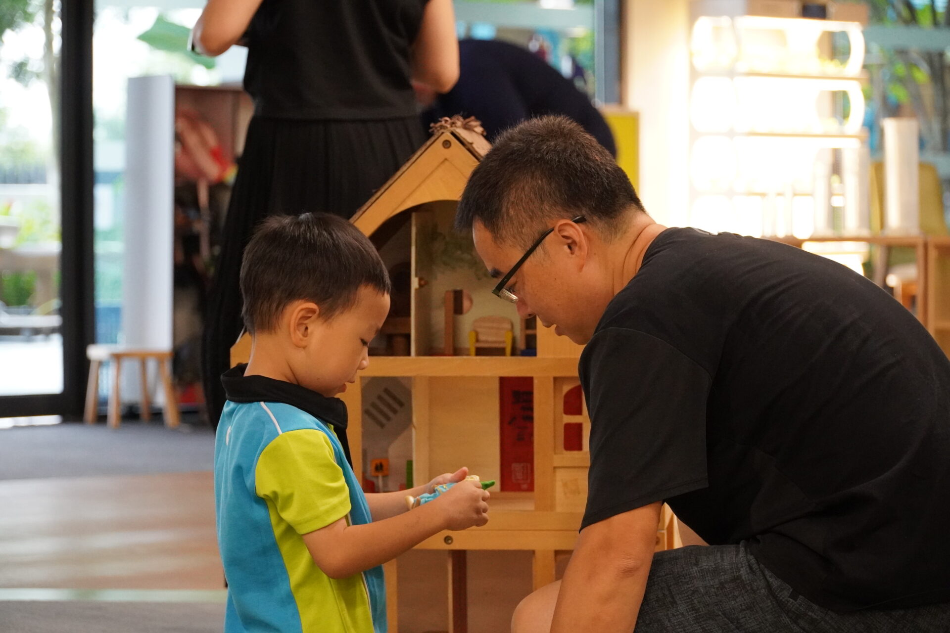 Father playing with a dollhouse with his son