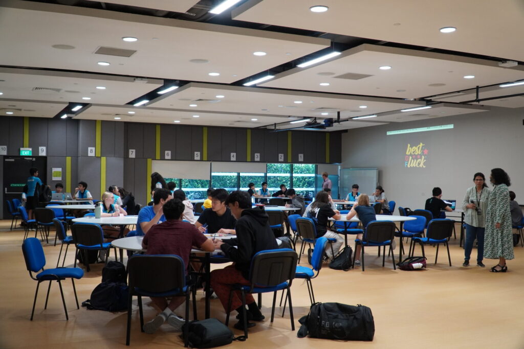 Students working in groups in a large hall for the Nexus Hackathon