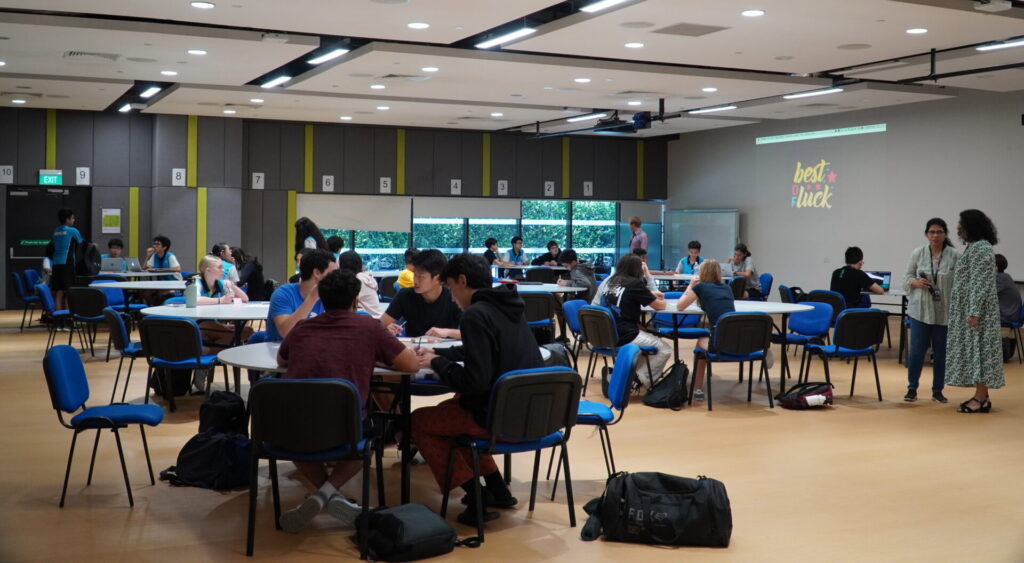 Students sitting in a large hall working in groups during a Hackathon